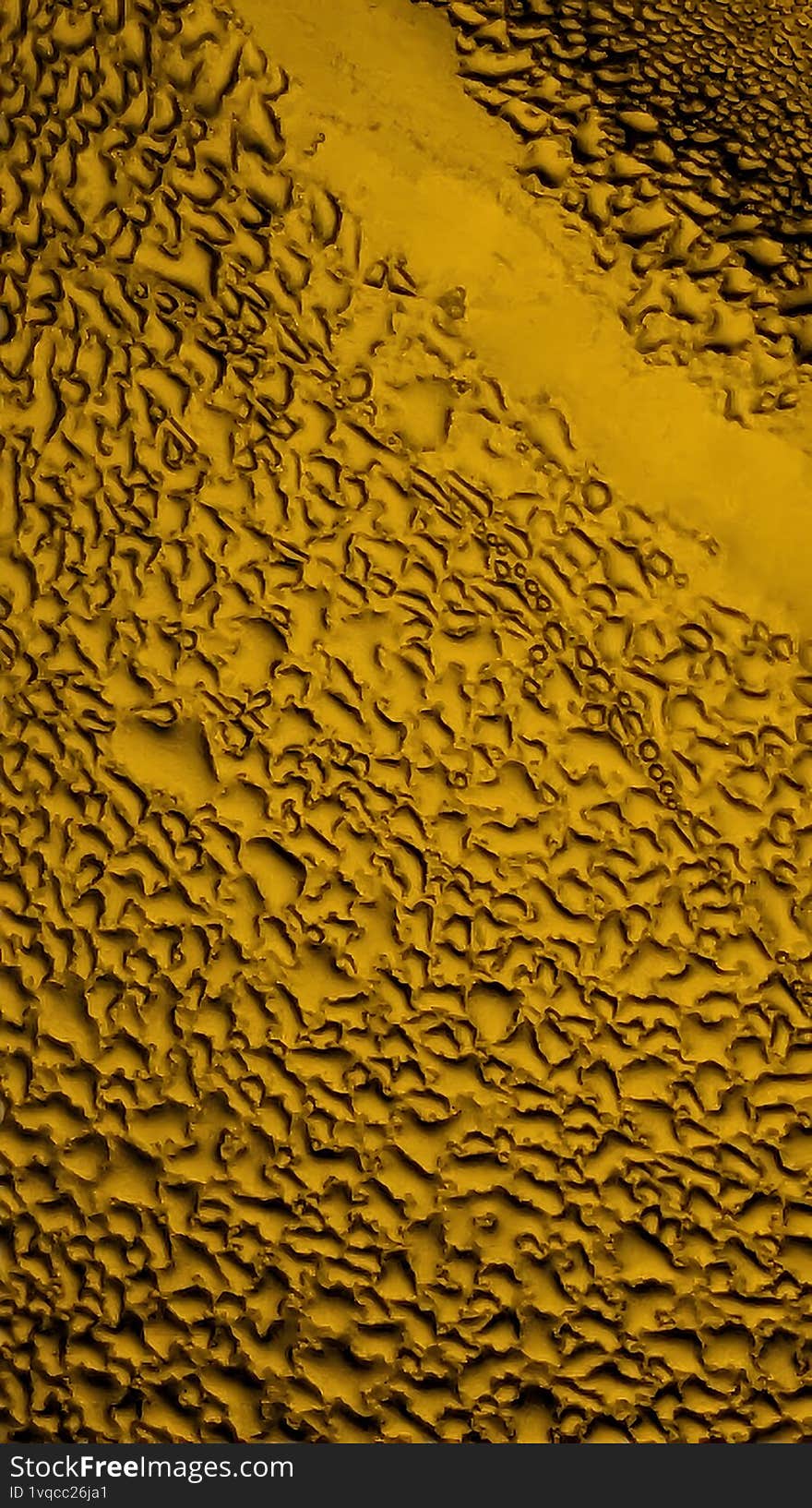 Dark drops and streaks on yellow glass form an expressive abstract, conveying mood, mystery, and depth. Ideal for conceptual or emotional design.