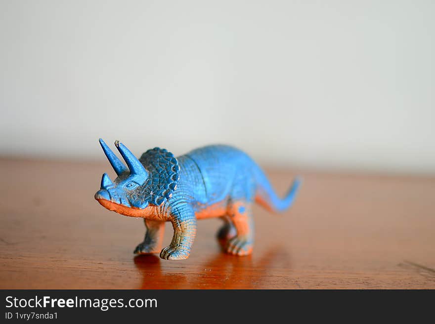 Blue Plastic Dinosaur Toy Displayed on Wooden Surface