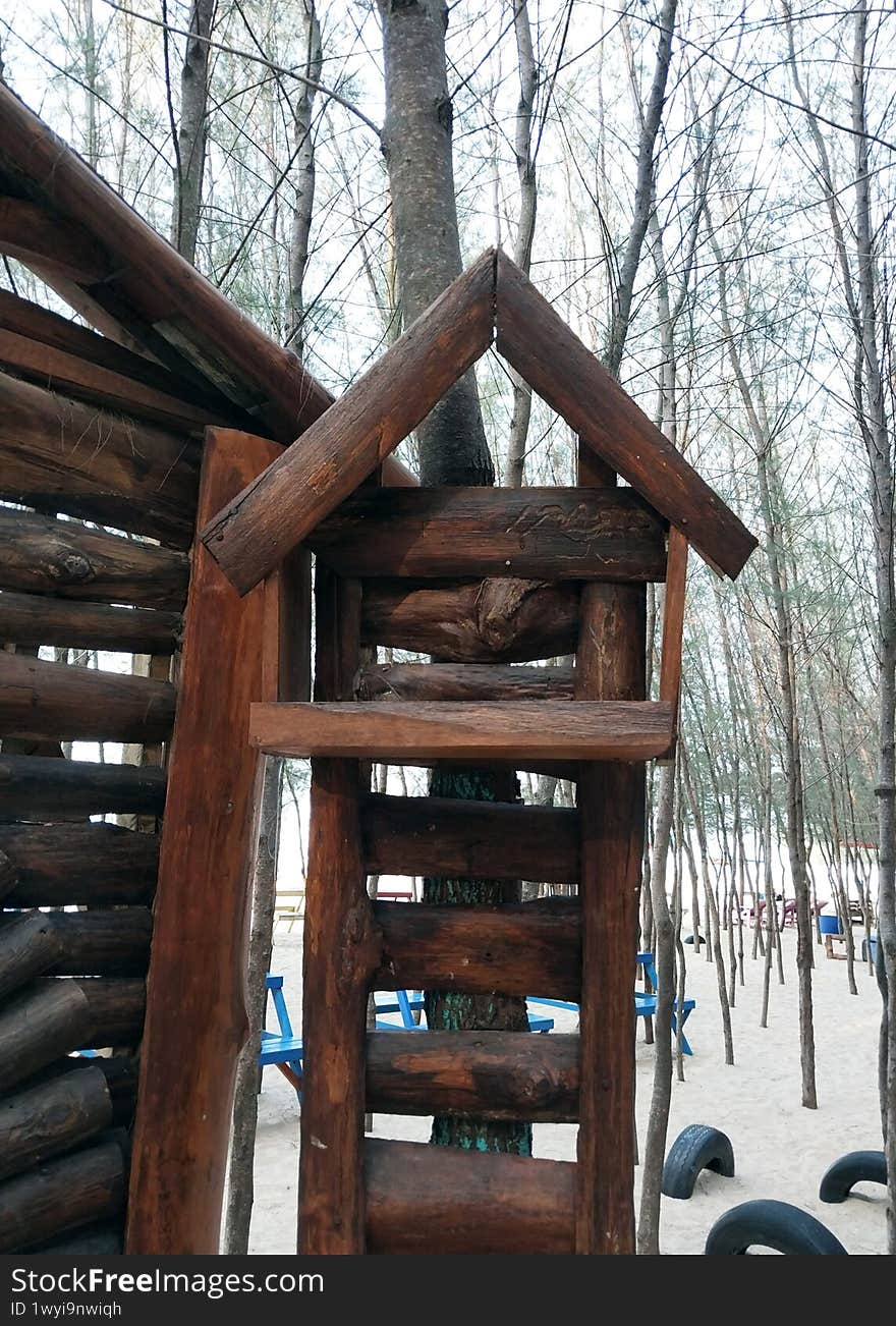 A rustic wooden playhouse nestled among tall trees, perfect for children's adventures. Its sturdy design blends seamlessly with nature, offering a safe and imaginative space for outdoor fun