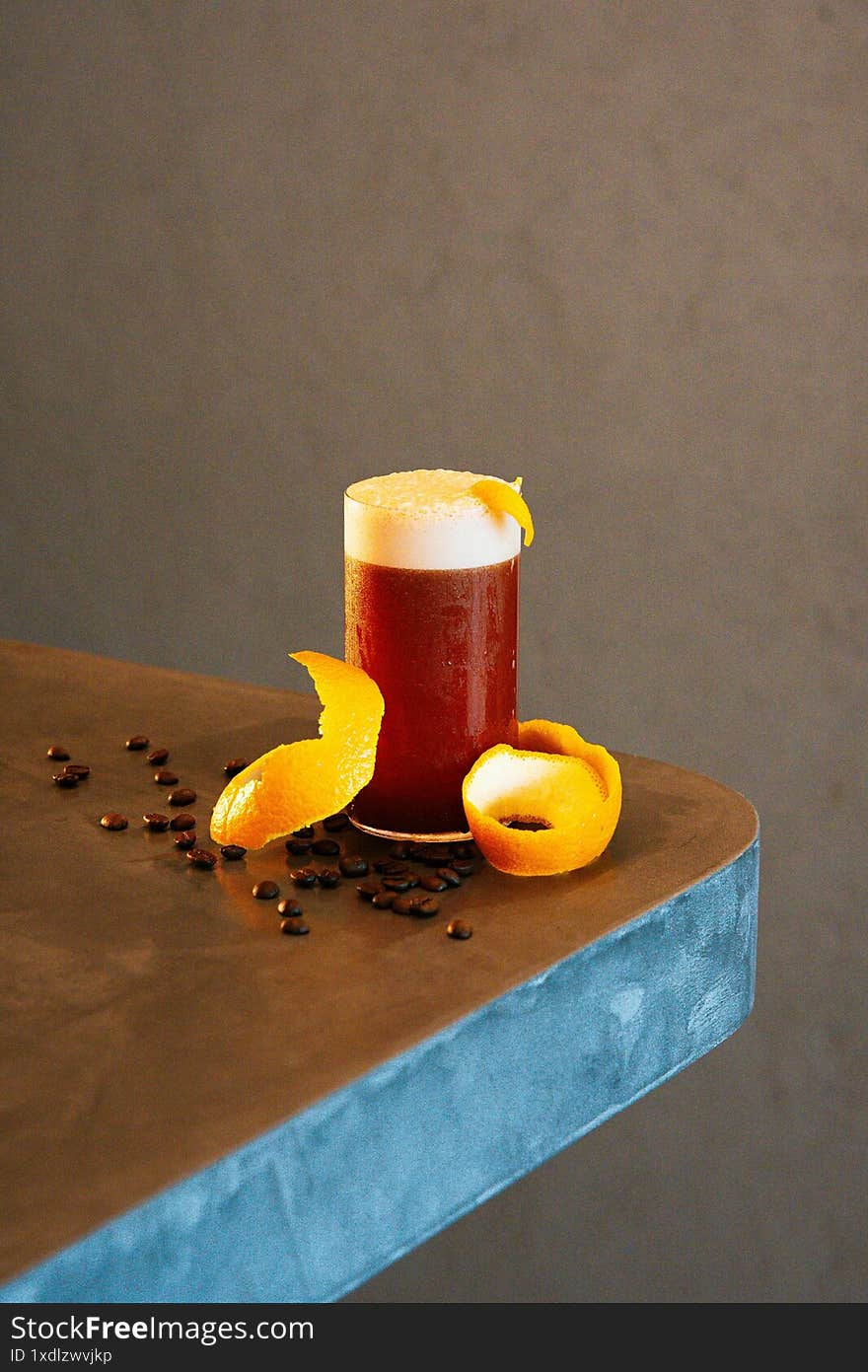 cup of beer with orange flakes and coffee grounds on table with beige backround