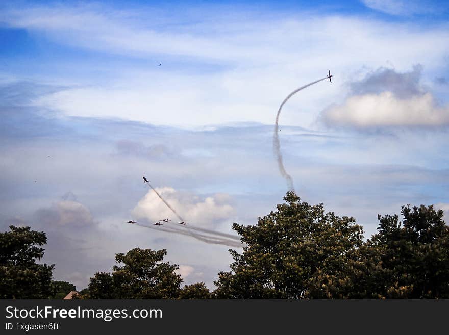 Manouver plane using white smoke with blue sky behind