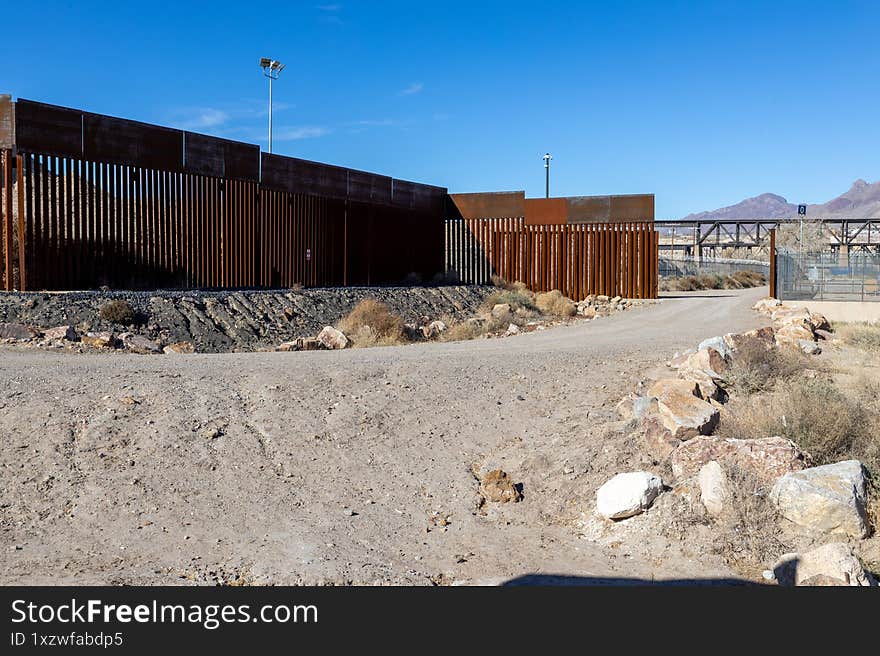 A towering wall, built from metal and concrete, stretches along a dusty path in the barren outskirts of Ciudad Juarez, a symbol of border immigration issues