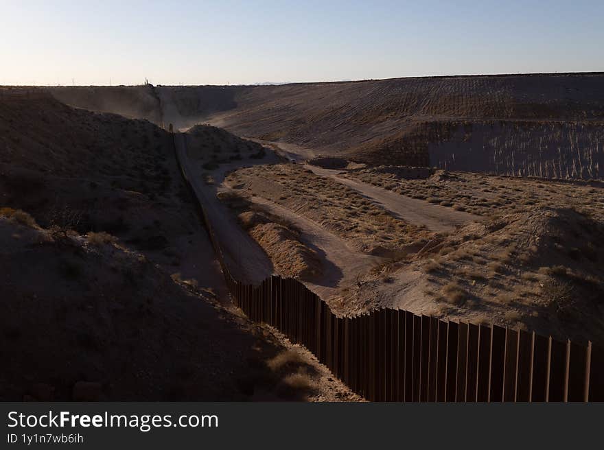 A long stretch of the border wall in Ciudad Juarez slices through arid terrain under a pristine sky