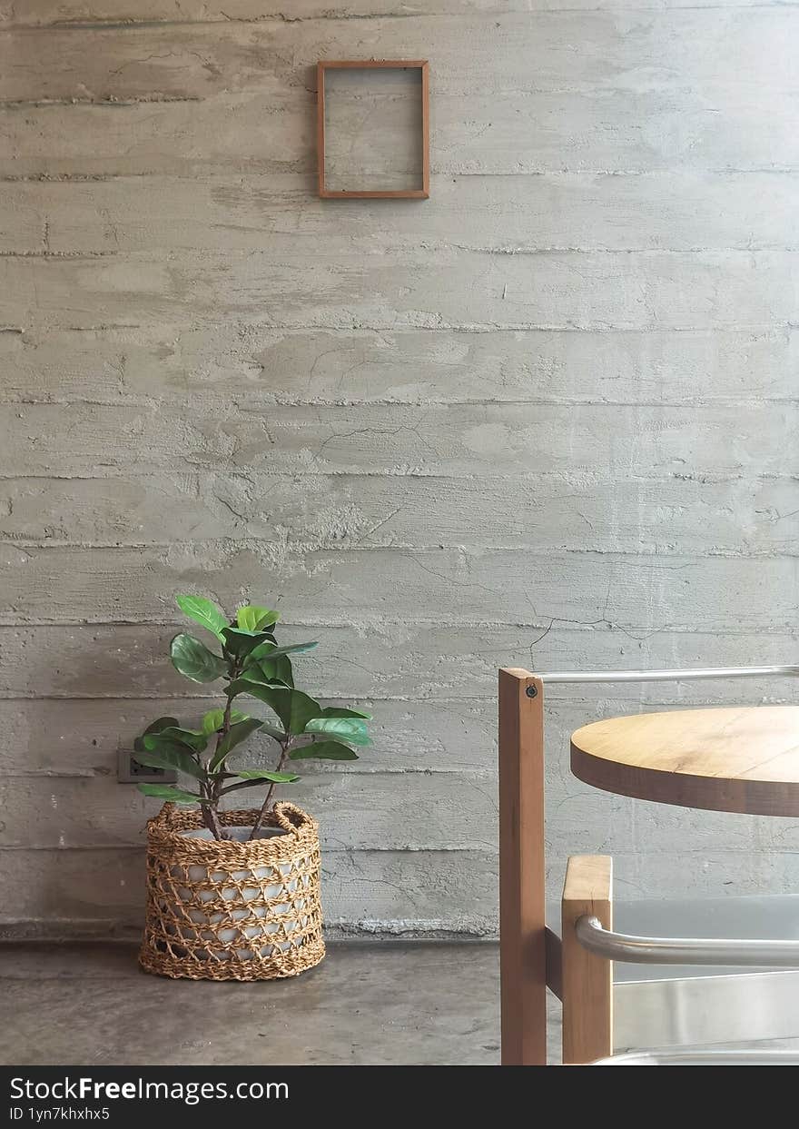Minimalist Interior with Green Plant in Woven Basket, Wooden Chair and Concrete Wall