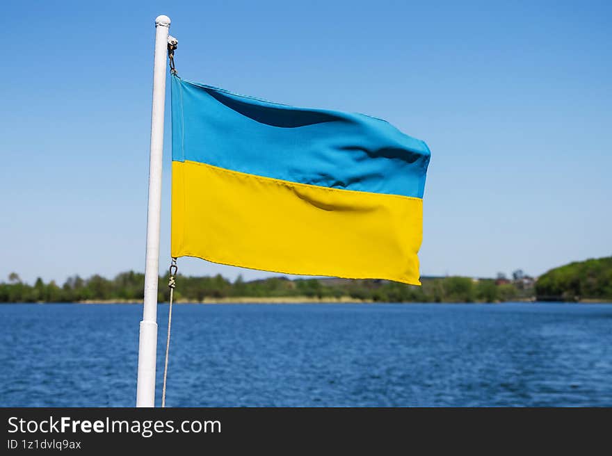 Flag of Ukraine flutters against background of water