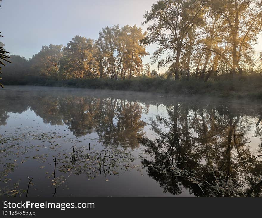 Early autumn morning with fog on the field and on the river