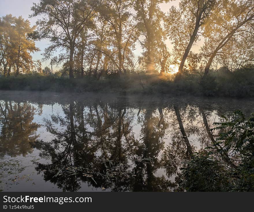 Early autumn morning with fog on the field and on the river