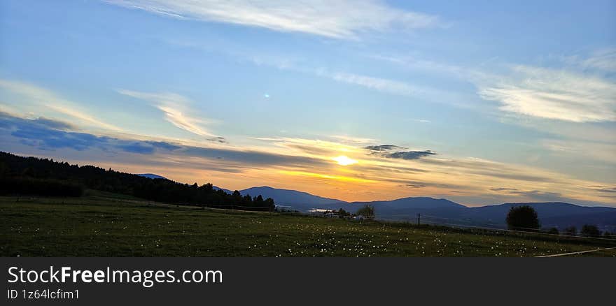 Sunset over Mountain Landscape with Fields and Hills