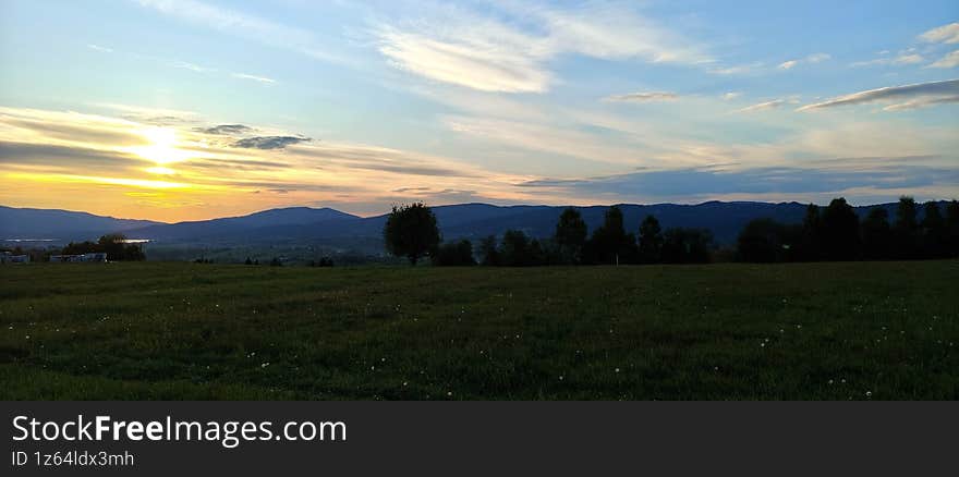Sunset over Mountain Landscape with Fields and Hills