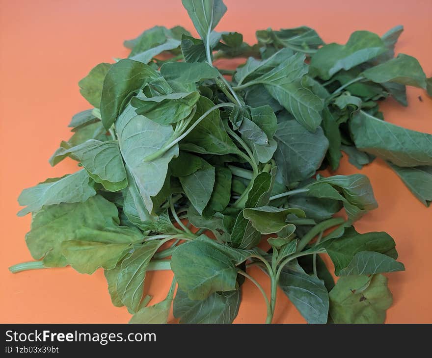 Fresh Green Spinach Leaves On Orange Background
