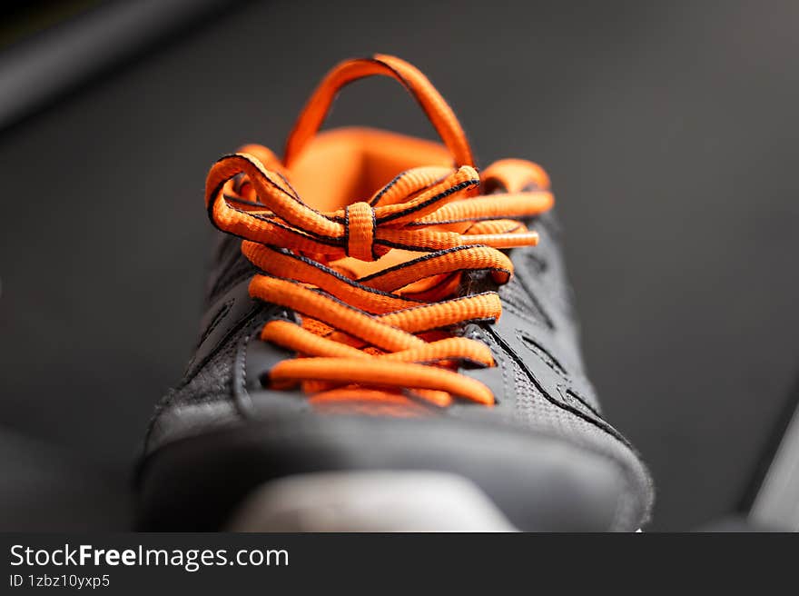 Sporty black sneaker with bright orange shoelaces in close-up. Concept of fitness, training, active lifestyle, running, and modern footwear design. Sporty black sneaker with bright orange shoelaces in close-up. Concept of fitness, training, active lifestyle, running, and modern footwear design.