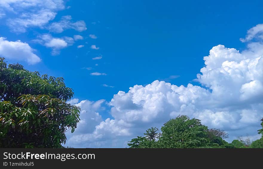 It was noon with a bright cloudy sky and a few trees below.