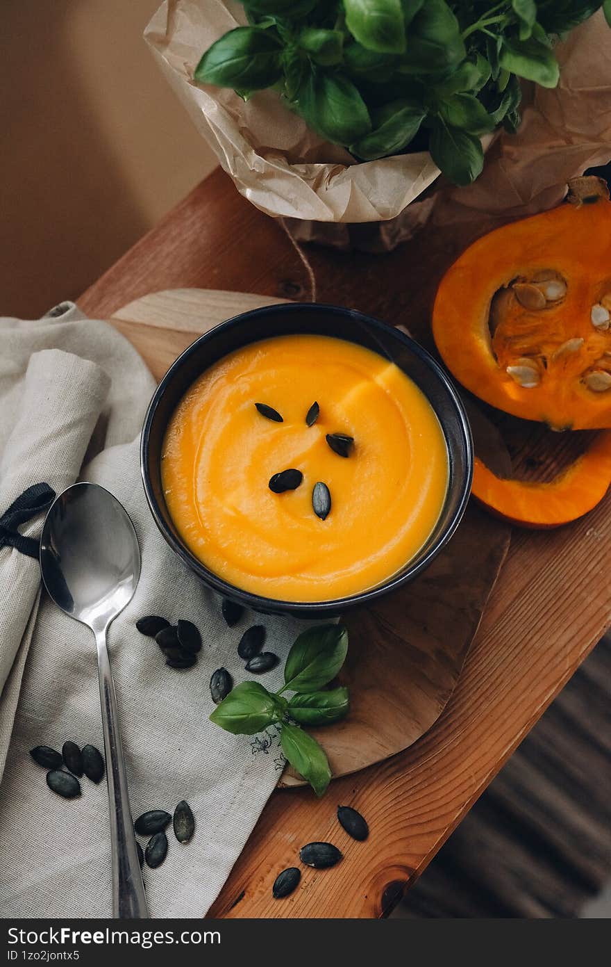 Still life of pumpkin soup garnished with fresh basil, highlighting warm autumn colors and cozy textures for an atmospheric season