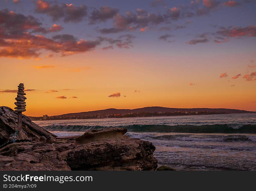 Artistic scene of balanced stones overlooking the sea and mountains during a golden sunset. Symbol of peace, balance, and harmony in nature. Artistic scene of balanced stones overlooking the sea and mountains during a golden sunset. Symbol of peace, balance, and harmony in nature.