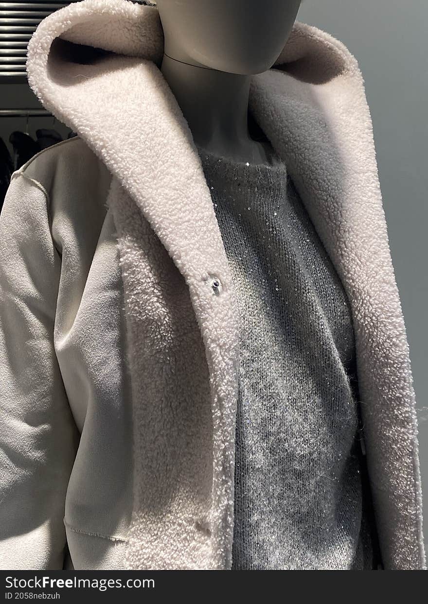 mannequin with female coat and gray sweater