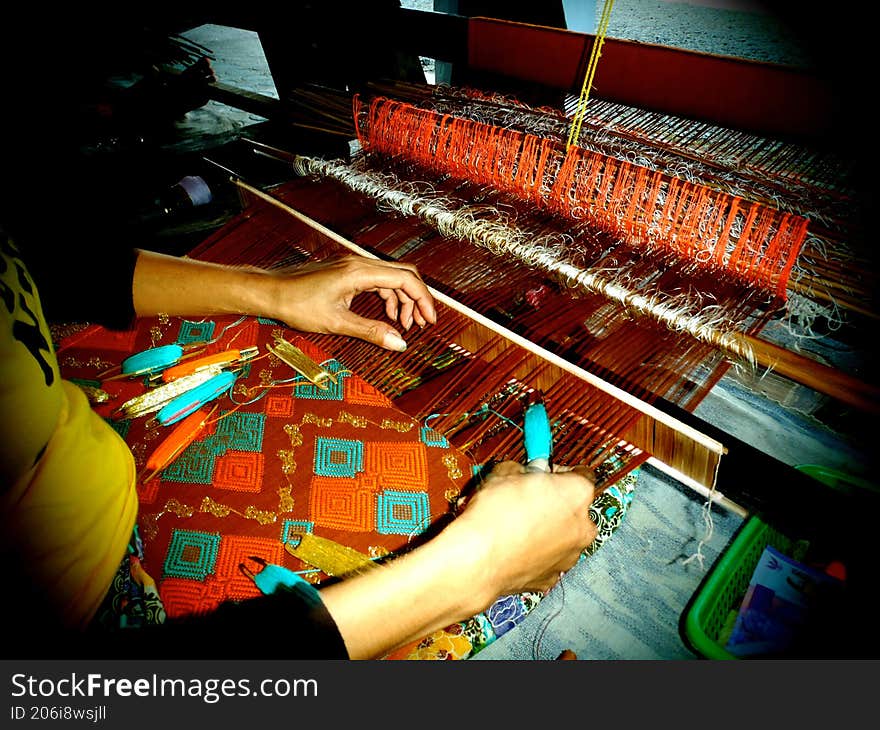 A person is weaving cloth in a village on Lombok Island, Indonesia