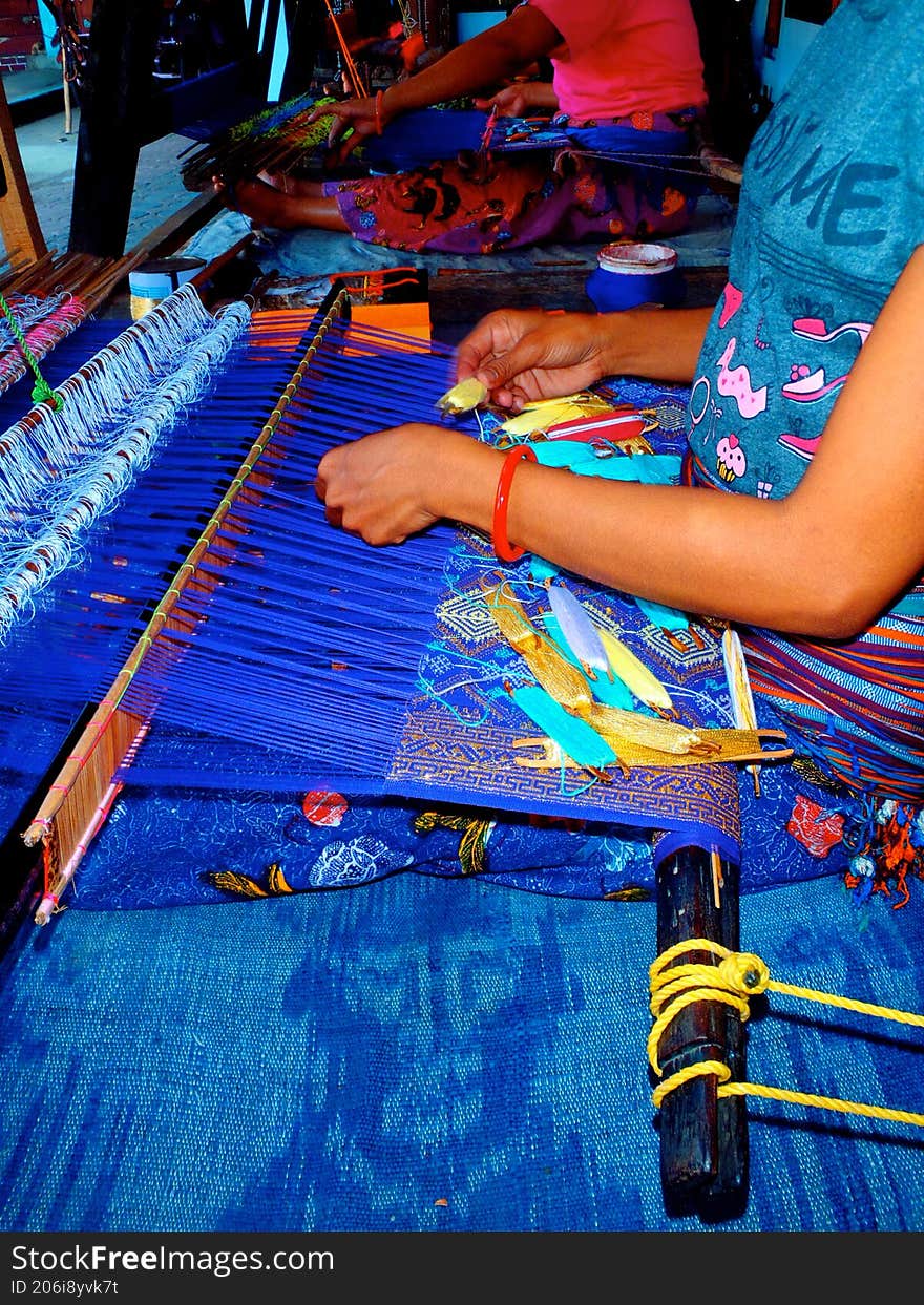 A person is weaving cloth in a village on Lombok Island, Indonesia