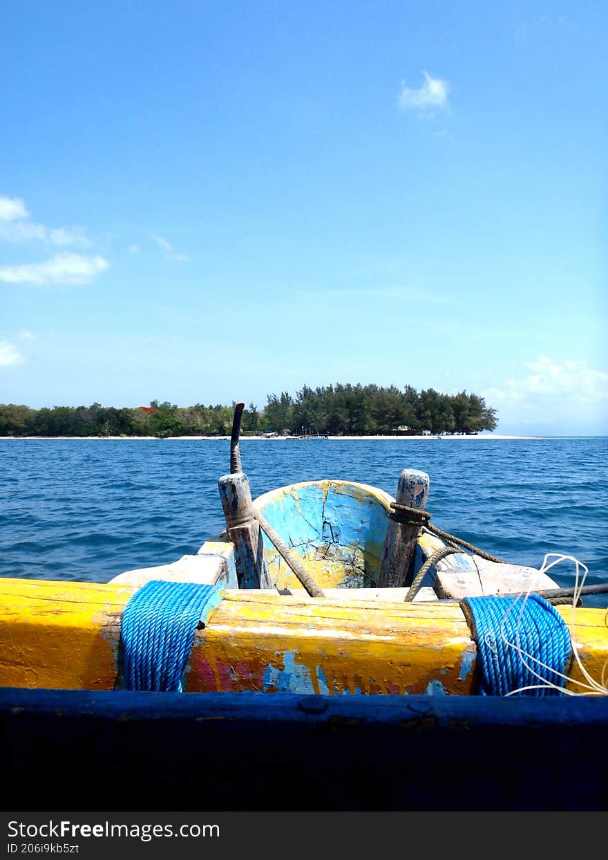 close up of the front end of a traditional wooden boat heading towards the island in front of it