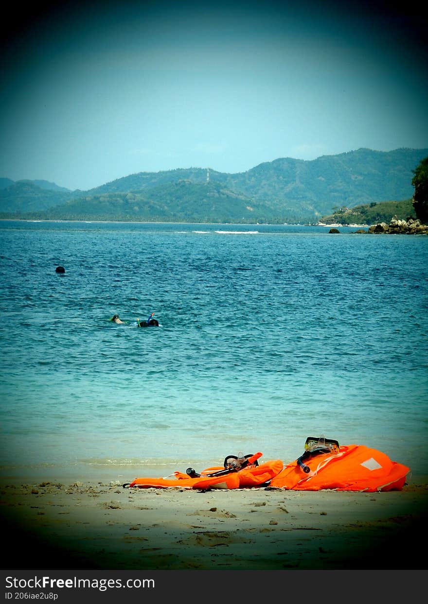 a life buoy stranded on the beach with a background of people snorkeling