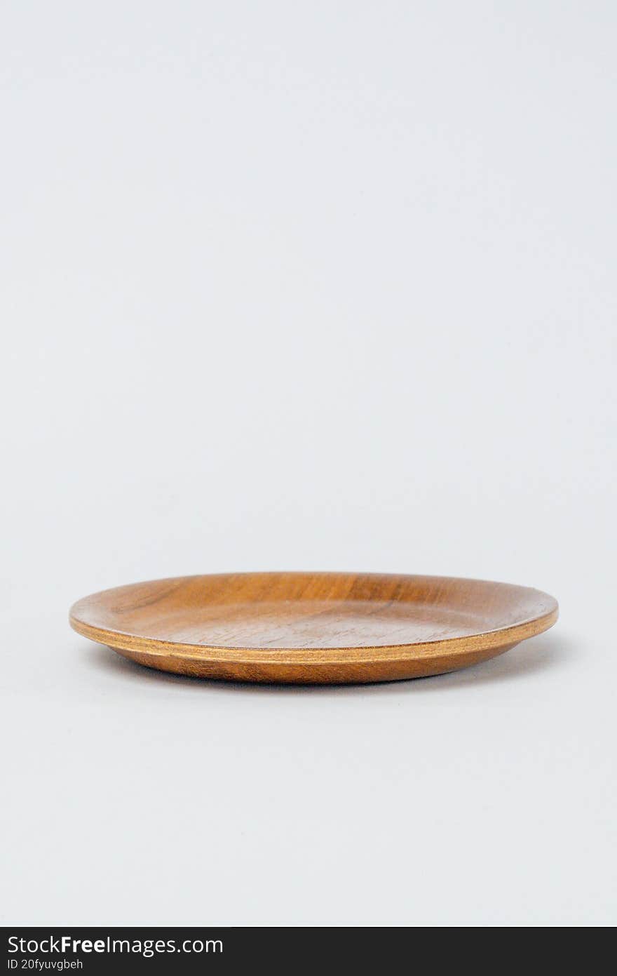 Side view empty round wooden plate on white