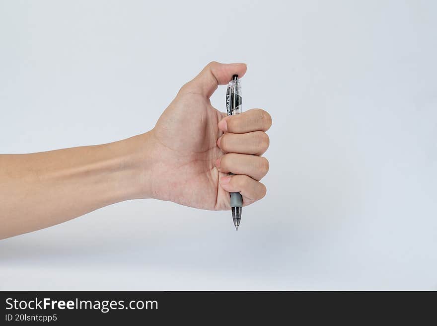 Hand gripping pen vertically on white background