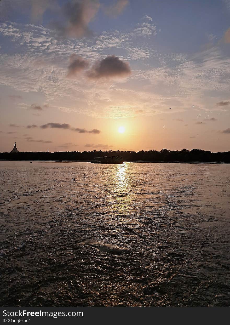 sun sets behind a low mountain range on horizon of a lake