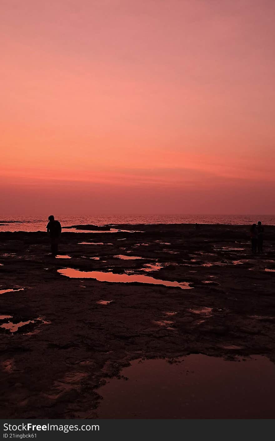 a sunset parting bright orange hues over a rocky sea shore