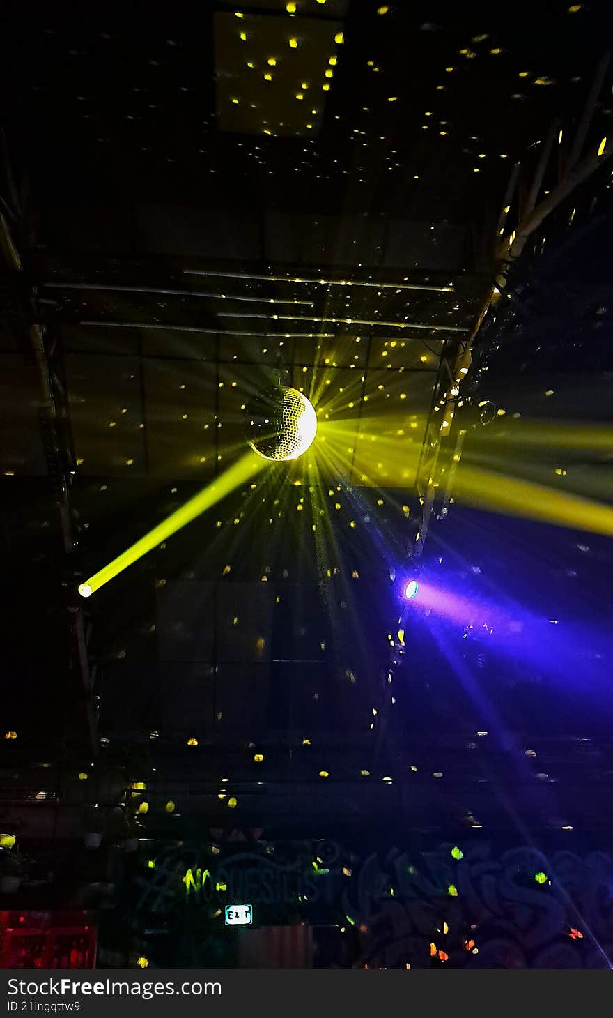 lots of spotlight reflecting off a disco ball and illuminating the walls with yellow lights in a night club