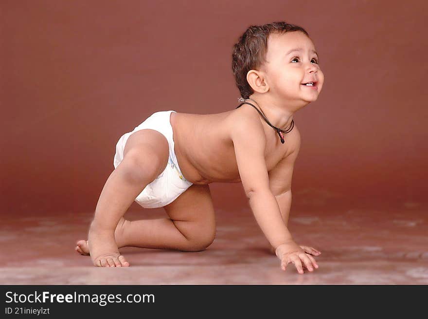 a cute baby girl crawling in a nappy, smiling , looking away from camera