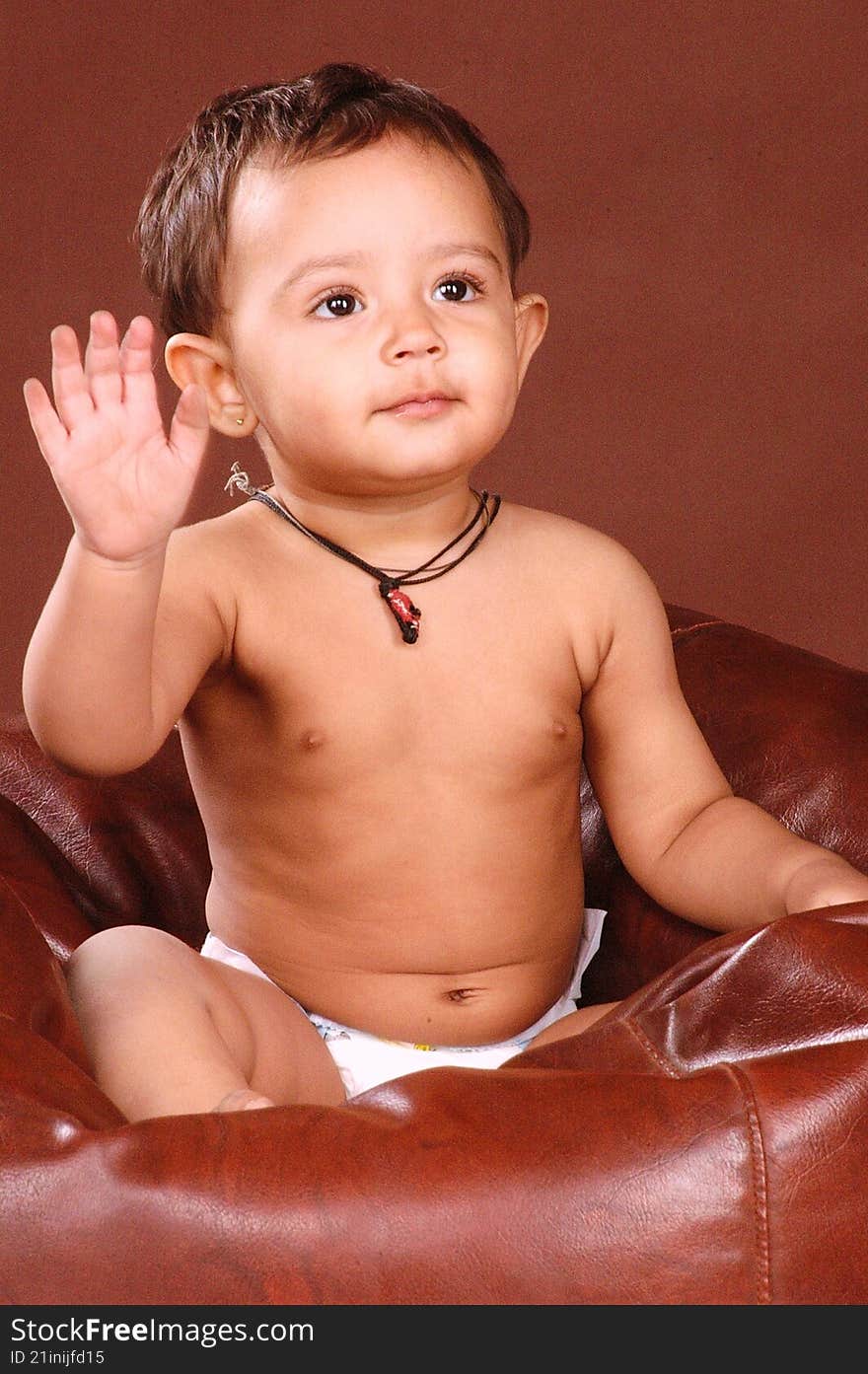a cute baby sitting in a bean bag, waving to the camera