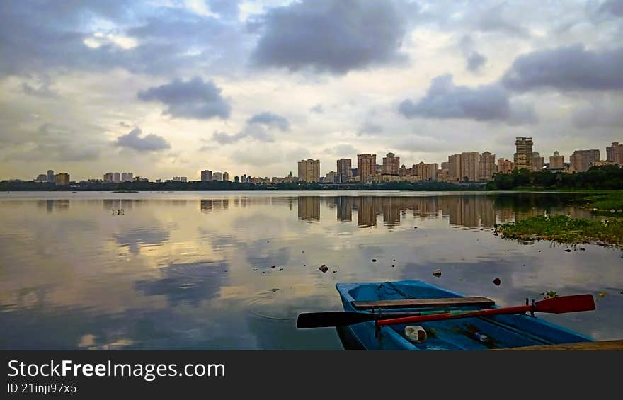 mesmerizing reflection of city skyline over a lake with a fishing boat and a paddle. sunrise time