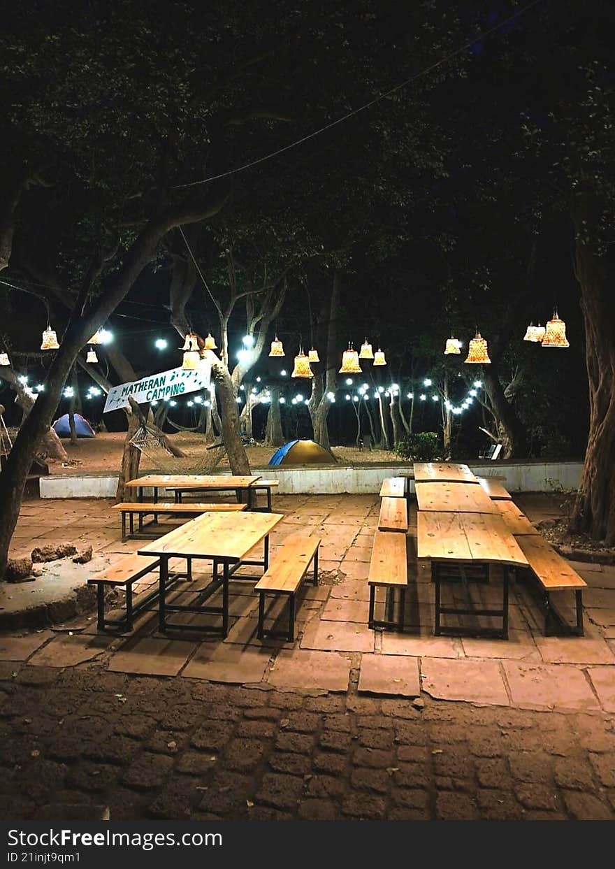 fairy lights glowing above benches with tents behind  matheran, India