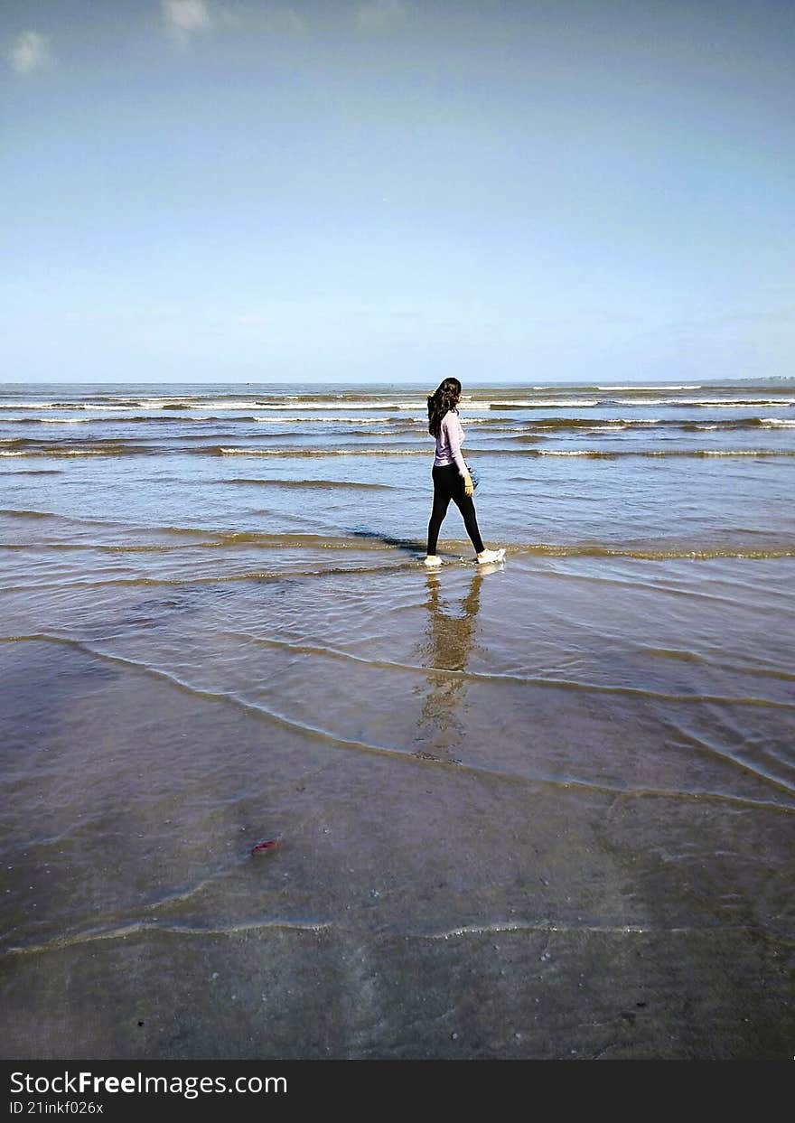 women walking on beach looking at the crashing waves on shore