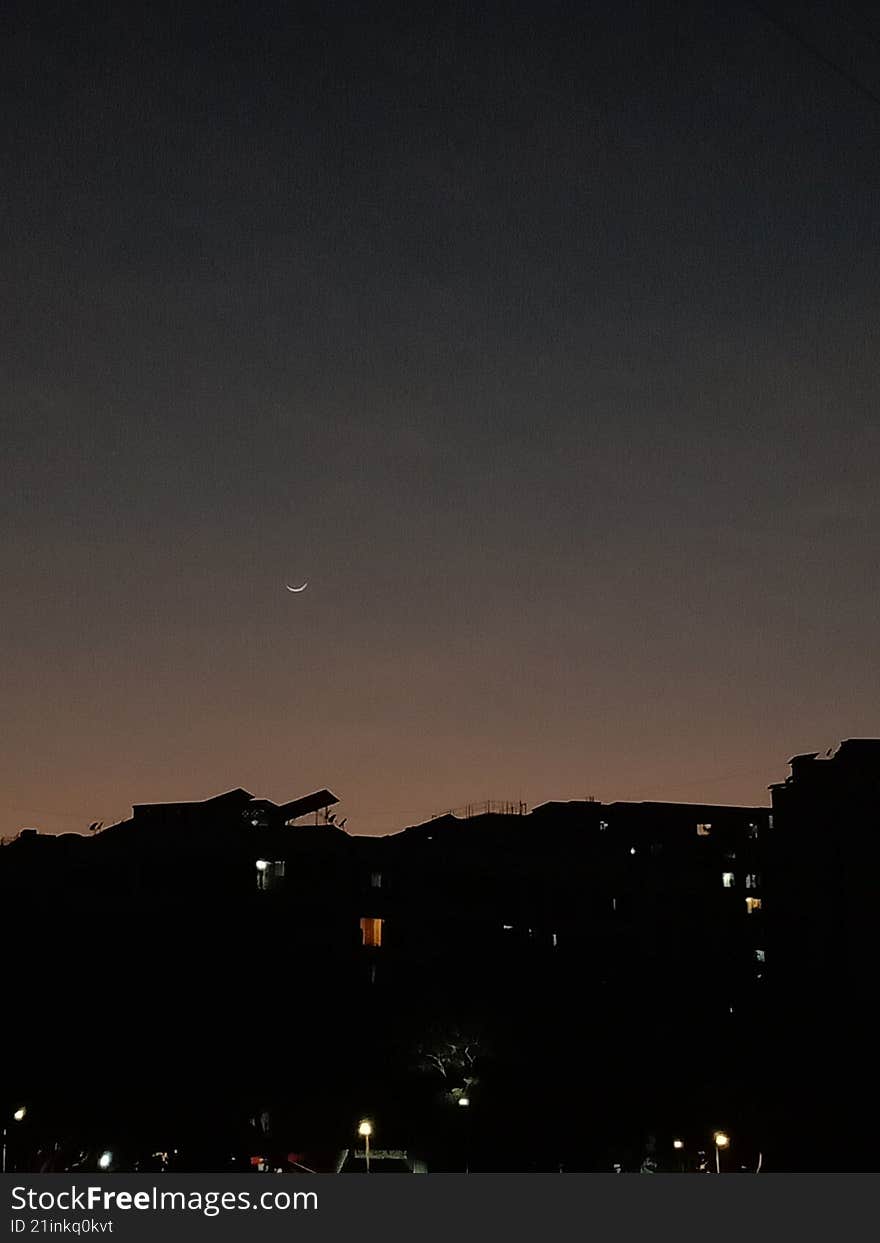 setting- down crescent moon over the town after sunset