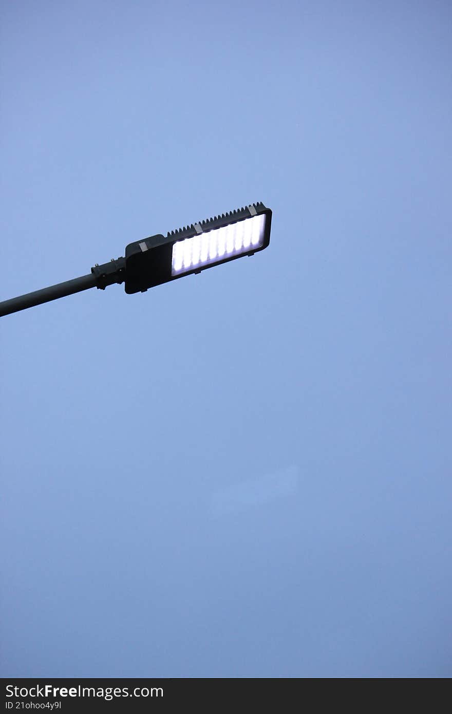 a modern LED streetlight against a clear, bright blue sky. The dominant colors are the bright white of the light and the clear blue, creating a clean and contemporary visual. a modern LED streetlight against a clear, bright blue sky. The dominant colors are the bright white of the light and the clear blue, creating a clean and contemporary visual