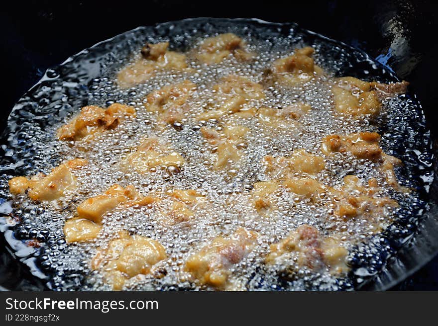 Close-up of golden fried meat balls bubbling in hot oil. A close-up photo showing meat balls being deep-fried in hot oil. The bubb
