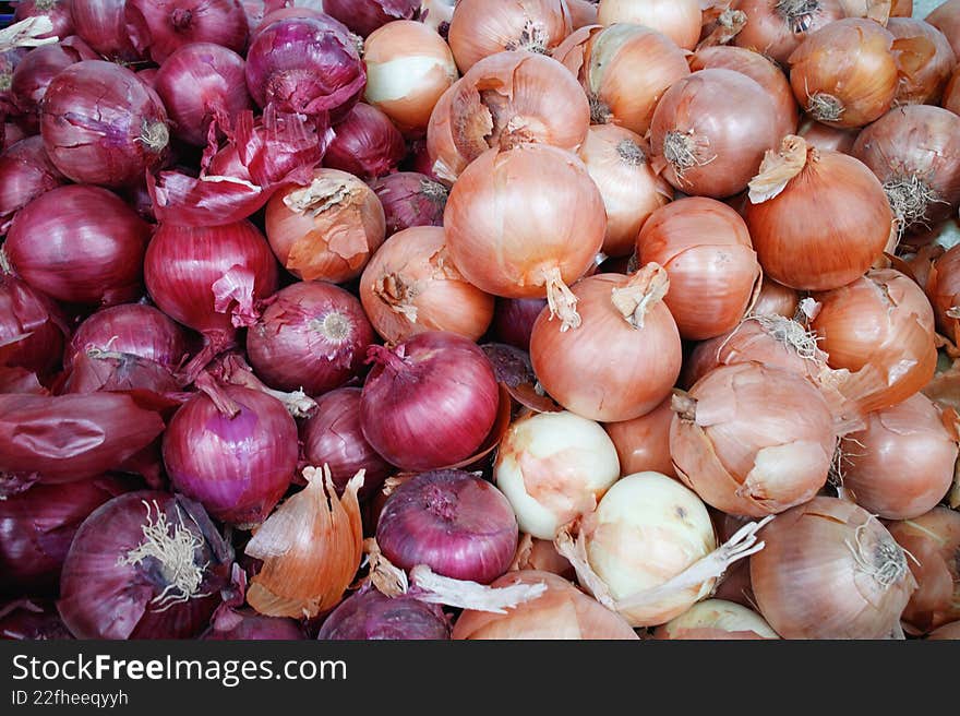 Close-up of a mixed stack of onions: purple onions and yellow onions.This image shows a close-up view of mixed onions, including r