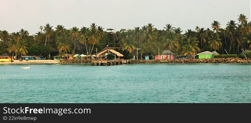 Serene Tropical Landscape With Palm Trees and Colorful Beach Huts at Sunset by the Water s Edge