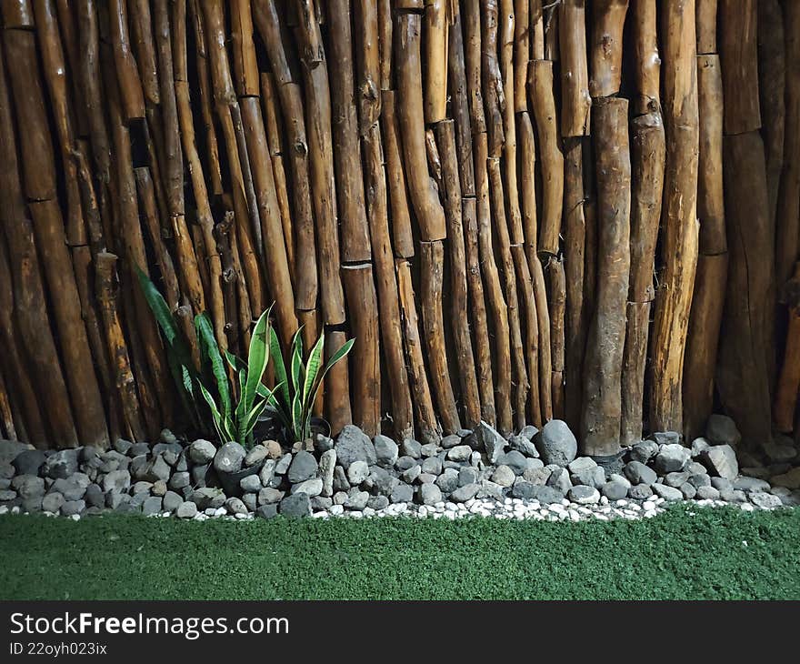 Rustic Wooden Log Wall with Green Snake Plants and Stone Garden Base