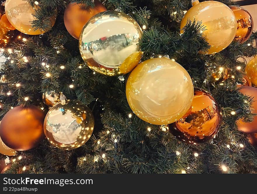Christmas card, shiny gold and bronze glass baubles on green pine needles.