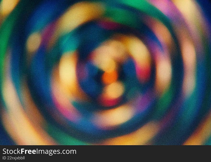 Blurred spiral patterns in shades of green, blue, orange, and purple. Artistic radial gradient backdrop with soft textures. Round shapes create a dynamic background for projects. Use for texture design, background illustration, and color concepts