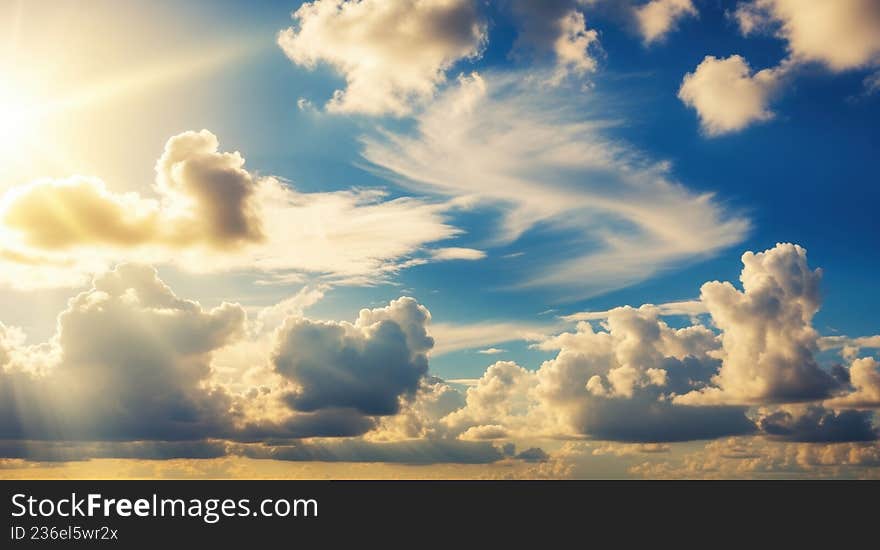 Golden sun rays breaking through dramatic clouds in blue sky