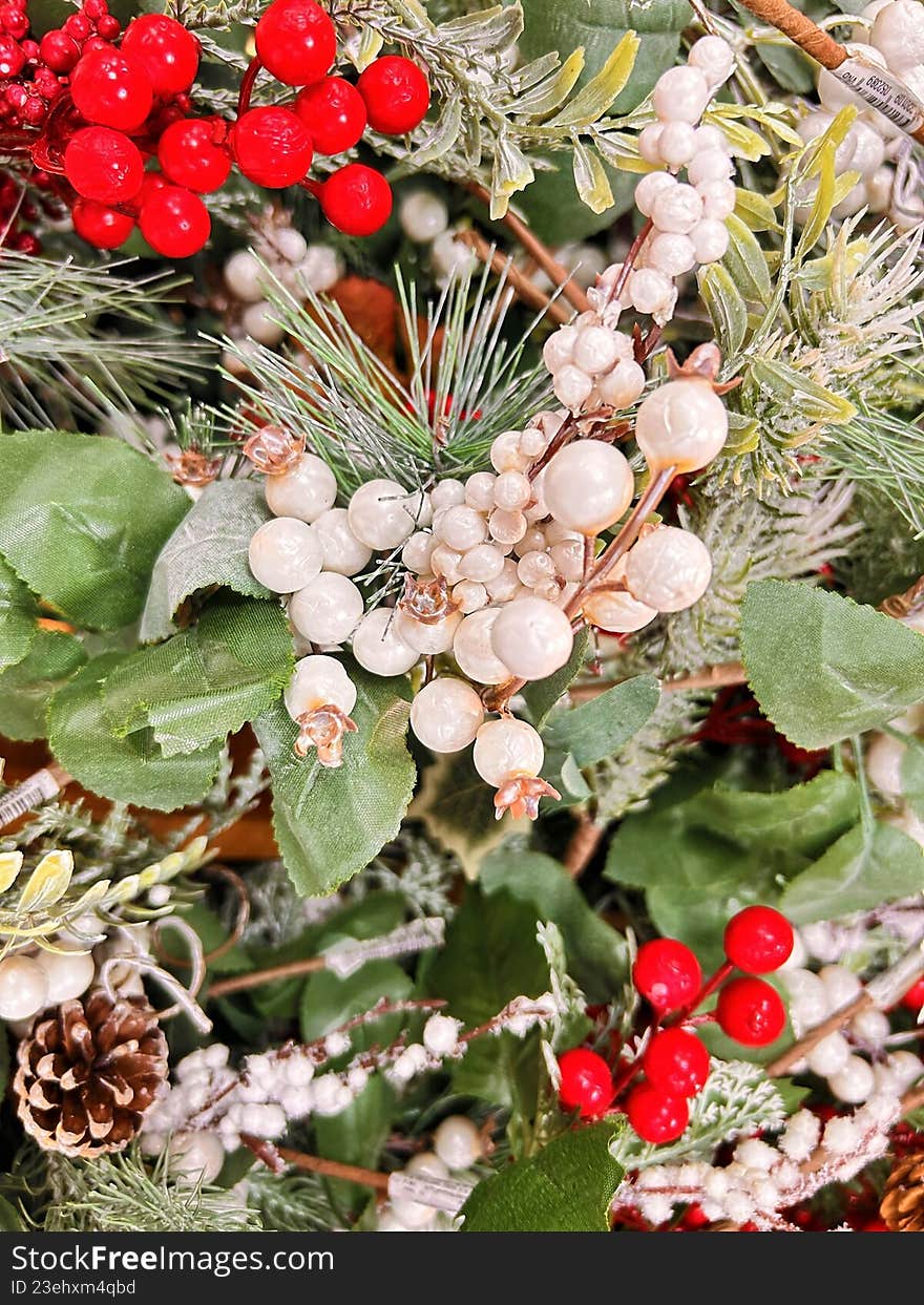 Christmas floral arrangement with red berries, white berries, pine branches, and natural greenery, symbolizing winter holidays and