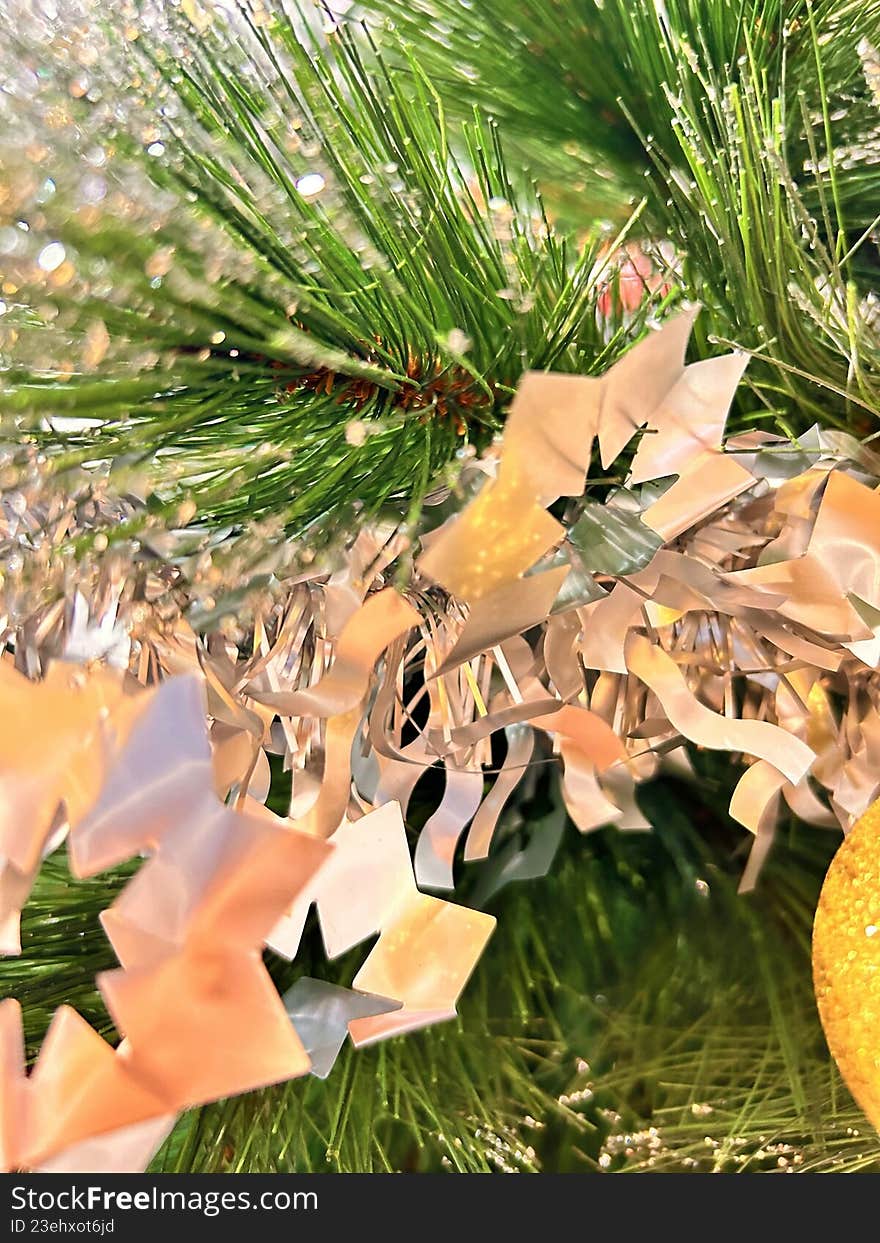 Golden star ornaments hanging on green Christmas tree branches, creating a warm and elegant holiday atmosphere.