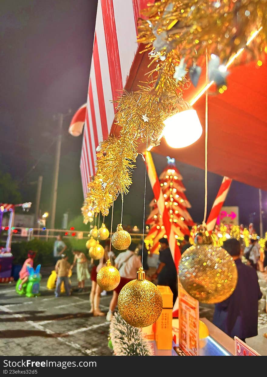 Outdoor Christmas street decoration with golden ornaments and lights at night, creating a lively and festive holiday atmosphere.