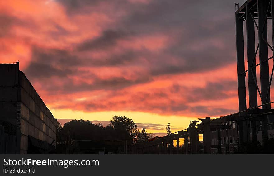 Industrial structure silhouettes against a vibrant, fire red sunset sky, symbolizing decay, abandonment, and pollution. Industrial structure silhouettes against a vibrant, fire red sunset sky, symbolizing decay, abandonment, and pollution