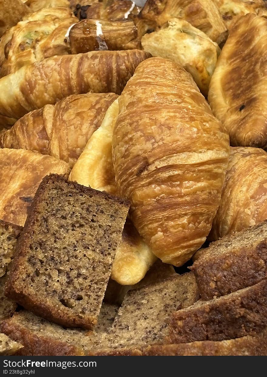 A high-angle, close-up shot of several freshly baked croissants resting on white parchment paper. The image highlights the golden