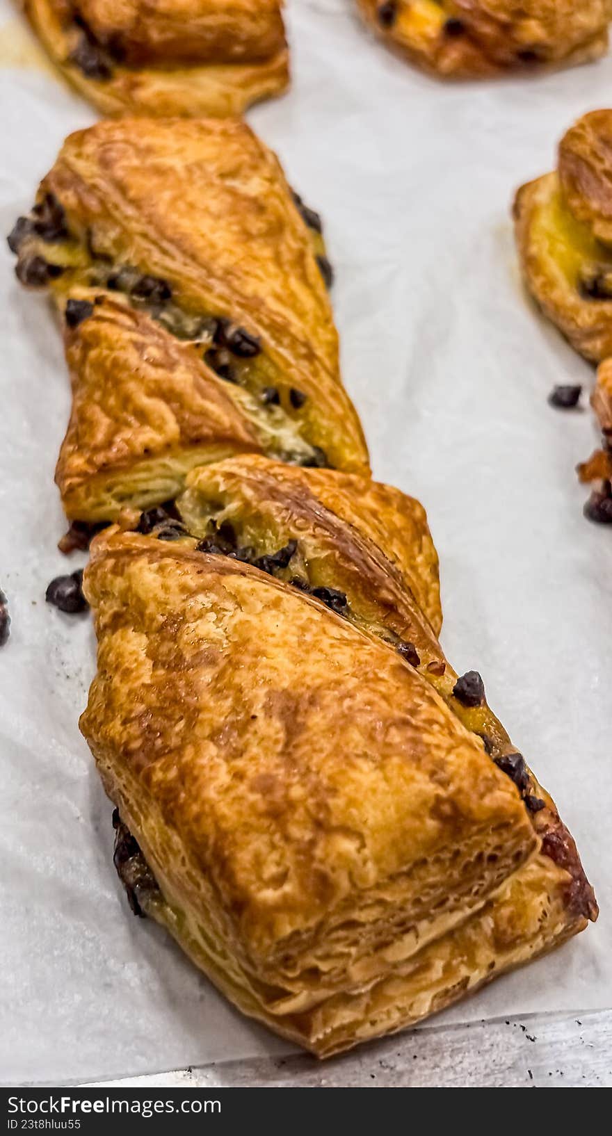 A high-angle, close-up shot of several freshly baked croissants resting on white parchment paper. The image highlights the golden