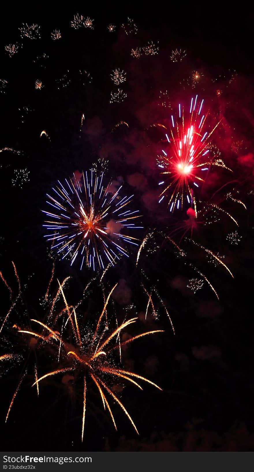 Fireworks in the night sky for new year festival celebration eve showing different multiple colors like yellow orange blue red golden colour. Three fireworks explosion in same photo