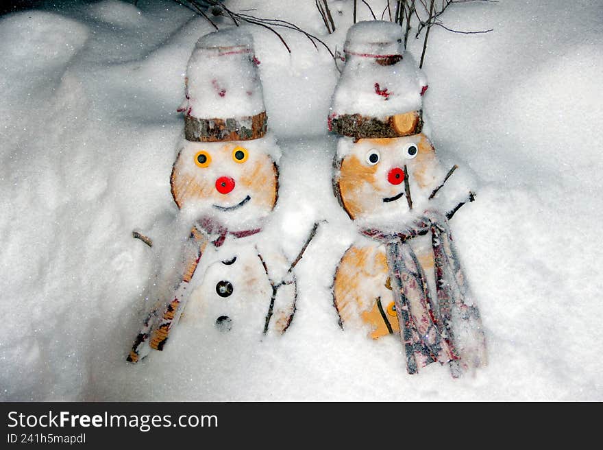 a pair of wooden snowmen in a snowdrift of sparkling snow